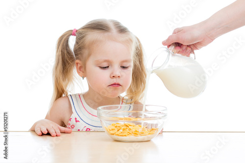 Photo: kid girl eating corn flakes with milk over white kid girl eating corn flakes with milk over white