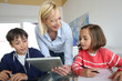 Photo: Teacher in class with kids using electronic tablet Teacher in class with kids using electronic tablet