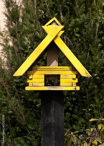 Photo: Gelbes Vogelhäuschen aus Holz auf einem Pfahl Gelbes Vogelhäuschen aus Holz auf einem Pfahl