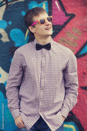 Photo: Style teen in glasses standing near graffiti wall. Style teen in glasses standing near graffiti wall.