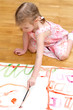 Pretty little girl painting sitting on the floor