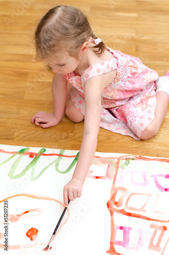 Photo: Pretty little girl painting sitting on the floor Pretty little girl painting sitting on the floor
