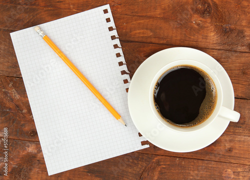 Photo: Cup of coffee on worktable covered with documents close up Cup of coffee on worktable covered with documents close up