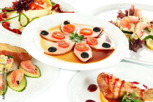 Photo: Small portions of food on big white plates close up Small portions of food on big white plates close up