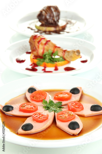 Photo: Small portions of food on big white plates isolated on white Small portions of food on big white plates isolated on white