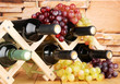 Bottles of wine placed on wooden stand on stone wall background