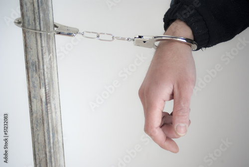 Photo: Close-up. Arrested man handcuffed on one hand Close-up. Arrested man handcuffed on one hand