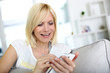 Smiling young woman at home using smartphone