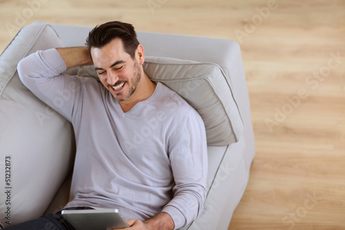 Photo: Upper view of man reading newspaper in sofa Upper view of man reading newspaper in sofa