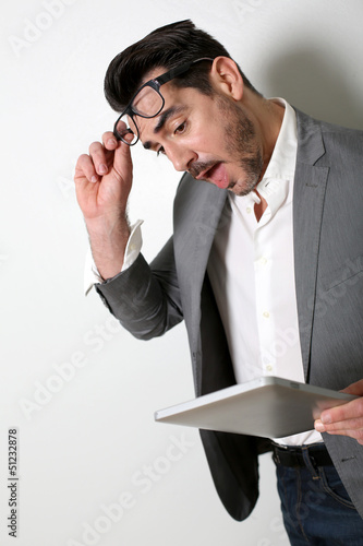 Photo: Man looking at tablet with surprised look Man looking at tablet with surprised look