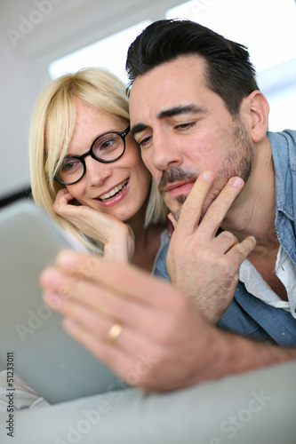 Photo: Cheerful couple websurfing on internet with tablet Cheerful couple websurfing on internet with tablet