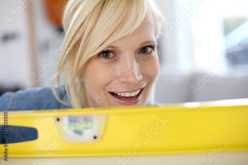 Photo: Closeup of blond woman looking through level Closeup of blond woman looking through level