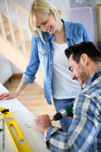 Photo: Couple installing furniture in new house Couple installing furniture in new house