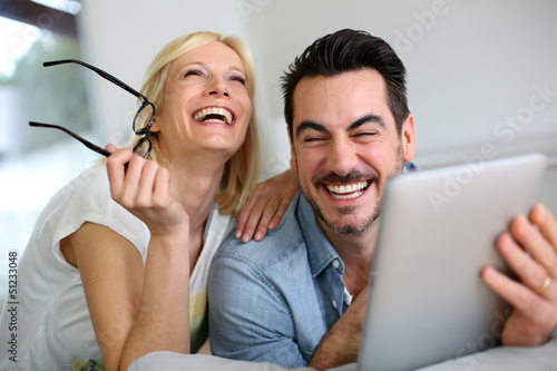 Photo: Cheerful couple websurfing on internet with tablet Cheerful couple websurfing on internet with tablet