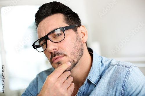 Photo: Trendy man with hand on chin looking at camera Trendy man with hand on chin looking at camera