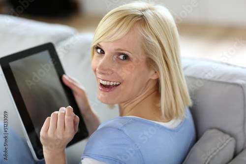 Photo: Smiling woman using tablet in sofa Smiling woman using tablet in sofa