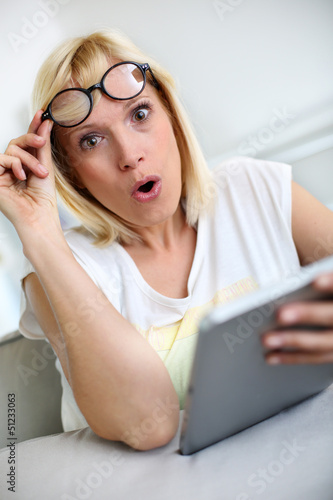 Photo: Funny girl in front of tablet with surprised look Funny girl in front of tablet with surprised look