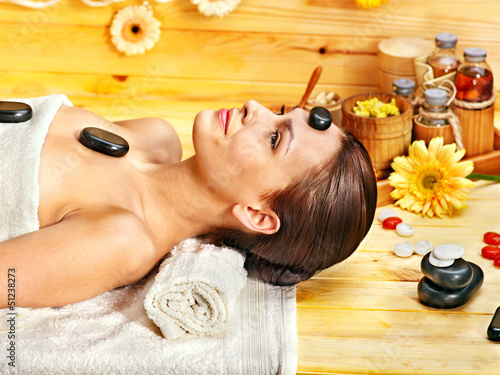 Photo: Woman getting stone therapy massage . Woman getting stone therapy massage .