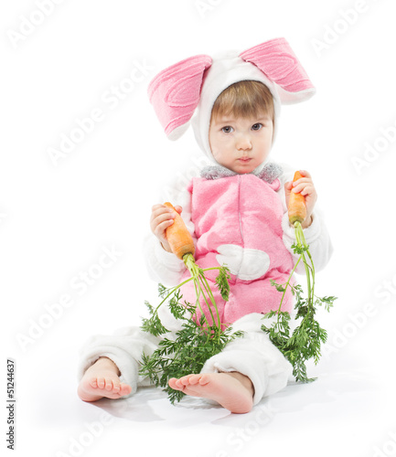 Photo: Child in bunny hare costume holding carrots. White background Child in bunny hare costume holding carrots. White background