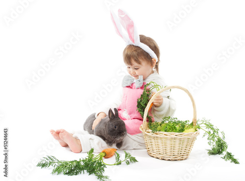 Photo: Child in bunny hare costume holding rabbit and carrot. Child in bunny hare costume holding rabbit and carrot.
