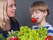 Photo: Mother trying to feed her little son with tomato Mother trying to feed her little son with tomato