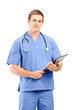 Foto: A male medical doctor in a uniform posing with clipboard in his A male medical doctor in a uniform posing with clipboard in his