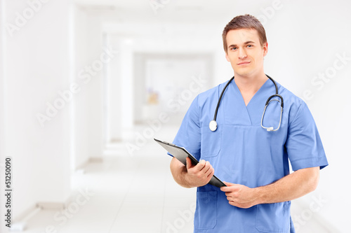 Photo: A male medical doctor in a uniform holding a clipboard and posin A male medical doctor in a uniform holding a clipboard and posin