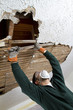 a young male pulls down plaster ceiling lathe with his hands