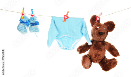 Photo: Baby clothes hanging on clothesline, isolated on white Baby clothes hanging on clothesline, isolated on white