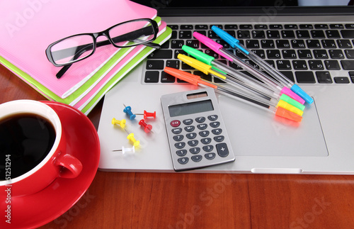 Photo: Laptop with stationery and cup of coffee on table Laptop with stationery and cup of coffee on table