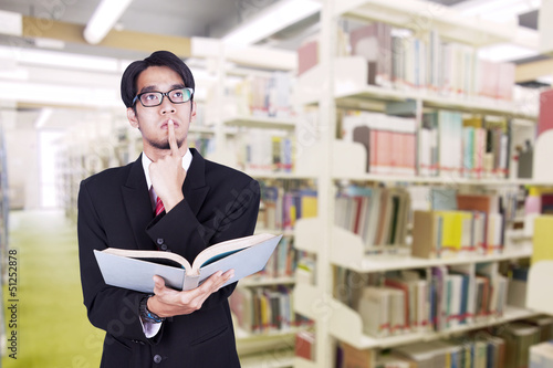 Photo: Businessman contemplating at library Businessman contemplating at library