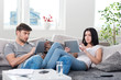 couple sitting on a couch with tablet computers