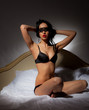 Girl in black lingerie in a mask sitting in bed