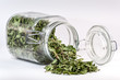Glass container with a tea leaf spilled on table