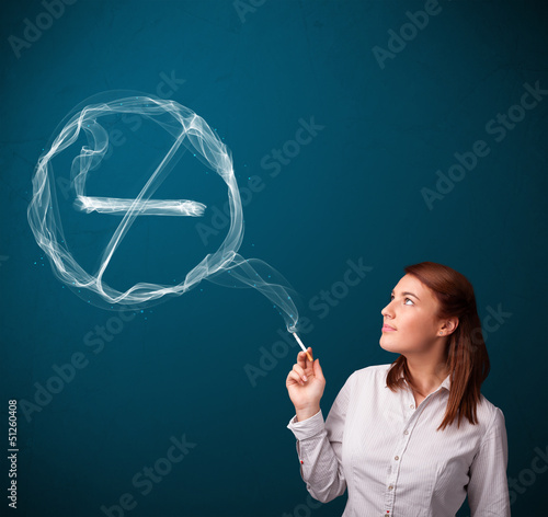 Photo: Young lady smoking unhealthy cigarette with no smoking sign Young lady smoking unhealthy cigarette with no smoking sign