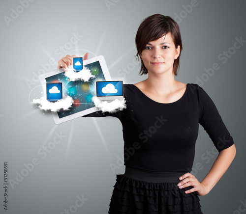 Photo: young woman holding tablet with modern devices in clouds young woman holding tablet with modern devices in clouds