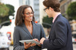 Businessman And Businesswoman Using Digital Tablet Outside