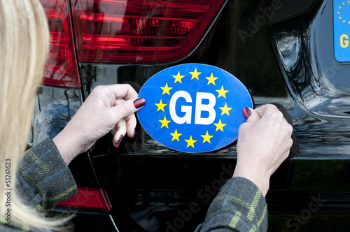 Photo: Motorist attaching GB sticker to car Motorist attaching GB sticker to car