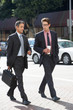 Two Businessman Chatting Whilst Crossing Street