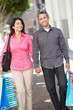 Photo: Couple Carrying Shopping Bags On City Street Couple Carrying Shopping Bags On City Street