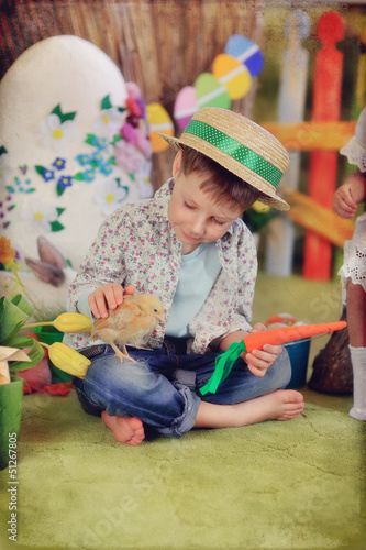 Photo: sits a wonderful boy in a straw hat with a chicken and carrots sits a wonderful boy in a straw hat with a chicken and carrots