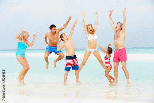 Photo: Multi Generation Family Having Fun In Sea On Beach Holiday Multi Generation Family Having Fun In Sea On Beach Holiday