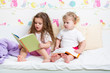 kids sisters reading a book in bed
