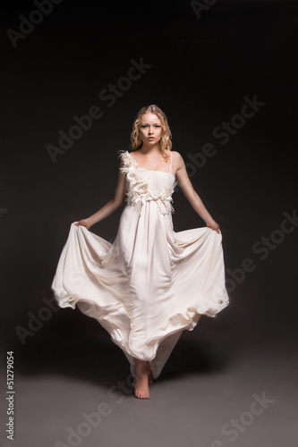 Photo: Dancing girl in wedding dress over dark background Dancing girl in wedding dress over dark background