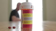 Prescription bottle with man in the background