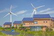 Roof with solar panels and wind turbines in the background