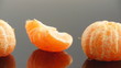 peeled tangerines on black mirror surface