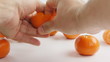 man clears tangerine of a peel