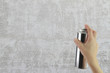 Human hand holding a graffiti Spray can in front of  wall