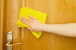 hand cleaning a door with a yellow cloth